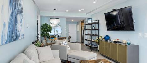 A modern living room with a sofa, coffee table, and a TV mounted on the wall.
