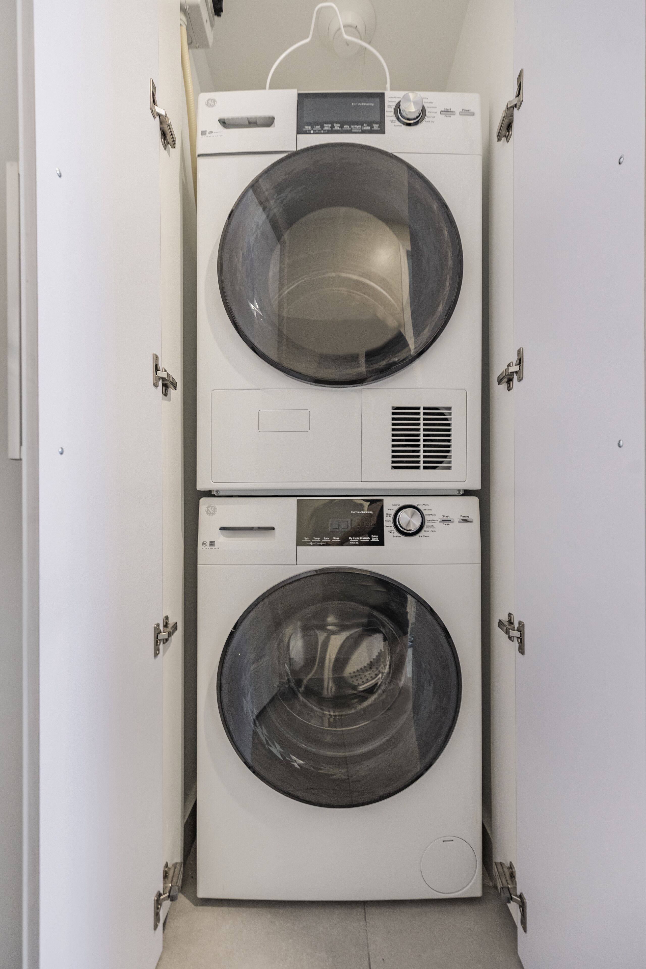Eine kompakte, weiße, übereinander angeordnete Waschmaschine und Trockner mit Bedienfeld oben und einer Frontlader-Waschmaschine darunter.