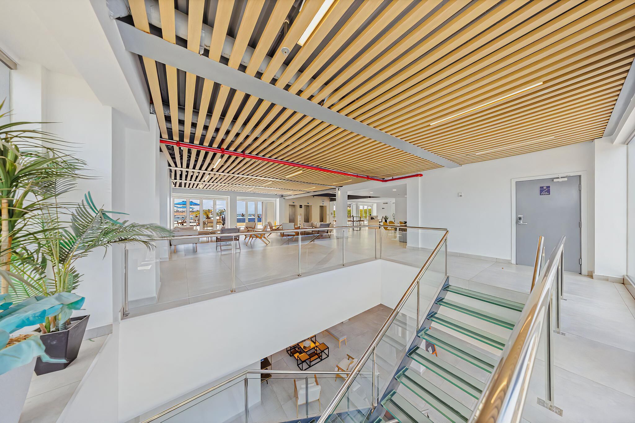 Un vaste espace intérieur doté d’un design moderne au niveau du plafond, de rampes en verre et d’un escalier.