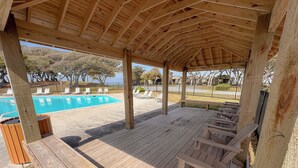 Eine Holzterrasse mit Liegestühlen, einem Pool und einem überdachten Bereich mit Blick auf den Pool.