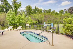 Relax by the serene pool surrounded by lush greenery and a secure fence, with lounge chairs and a metal ladder for easy access.
