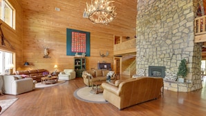 A spacious living area with wooden floors, a stone fireplace, and a cozy fireplace area.