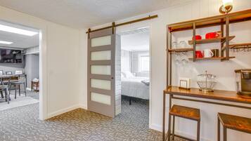 Une pièce dotée d’une porte coulissante donnant sur une chambre, d’un coin cuisine avec des étagères en bois et d’un tapis à motifs.