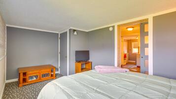 Une chambre à coucher comprenant un lit, une armoire en bois, un téléviseur et une porte donnant sur une autre pièce.