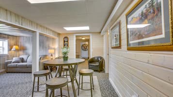 Une pièce chaleureuse avec un plancher en bois, une table ronde entourée de tabourets, un canapé et une lampe.