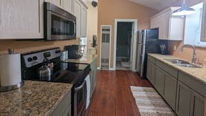 A kitchen with granite countertops, stainless steel appliances, and wooden cabinets. - Charming Couple's Cottage close to Lake Michigan, Silver lake, and Stoney Lake (Shelby)