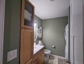 Une salle de bain avec un meuble-lavabo en bois, des toilettes et un espace douche.