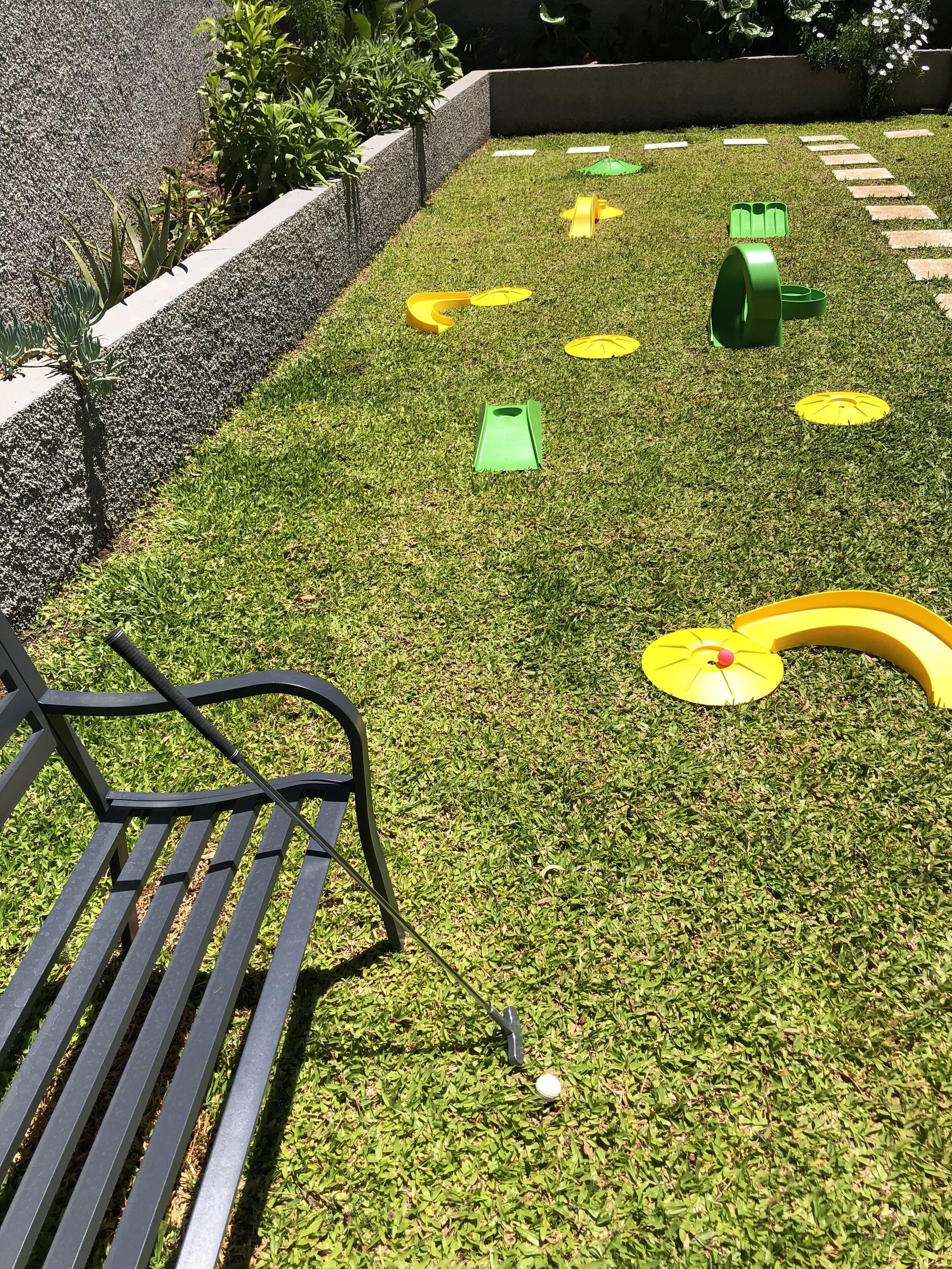 Ett välskött grönområde med en bänk och en puttinggreen för golf.