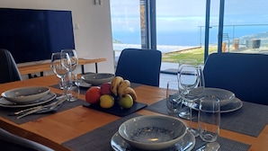 Una mesa de comedor dispuesta con platos, tazones, cubiertos y vasos, con un frutero y plátanos sobre la mesa.