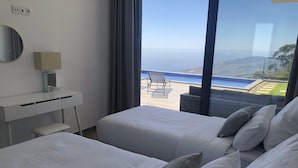 Habitación de hotel con dos camas, un escritorio y vistas a una piscina y al paisaje.