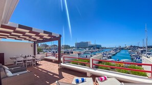 A rooftop terrace with outdoor seating and a view of a marina with boats.