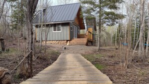 A wooden pathway leading to a cabin in a forest. - House of the Grouse -  Charming  River-side Cabin and Sauna!  (Grand Marais)