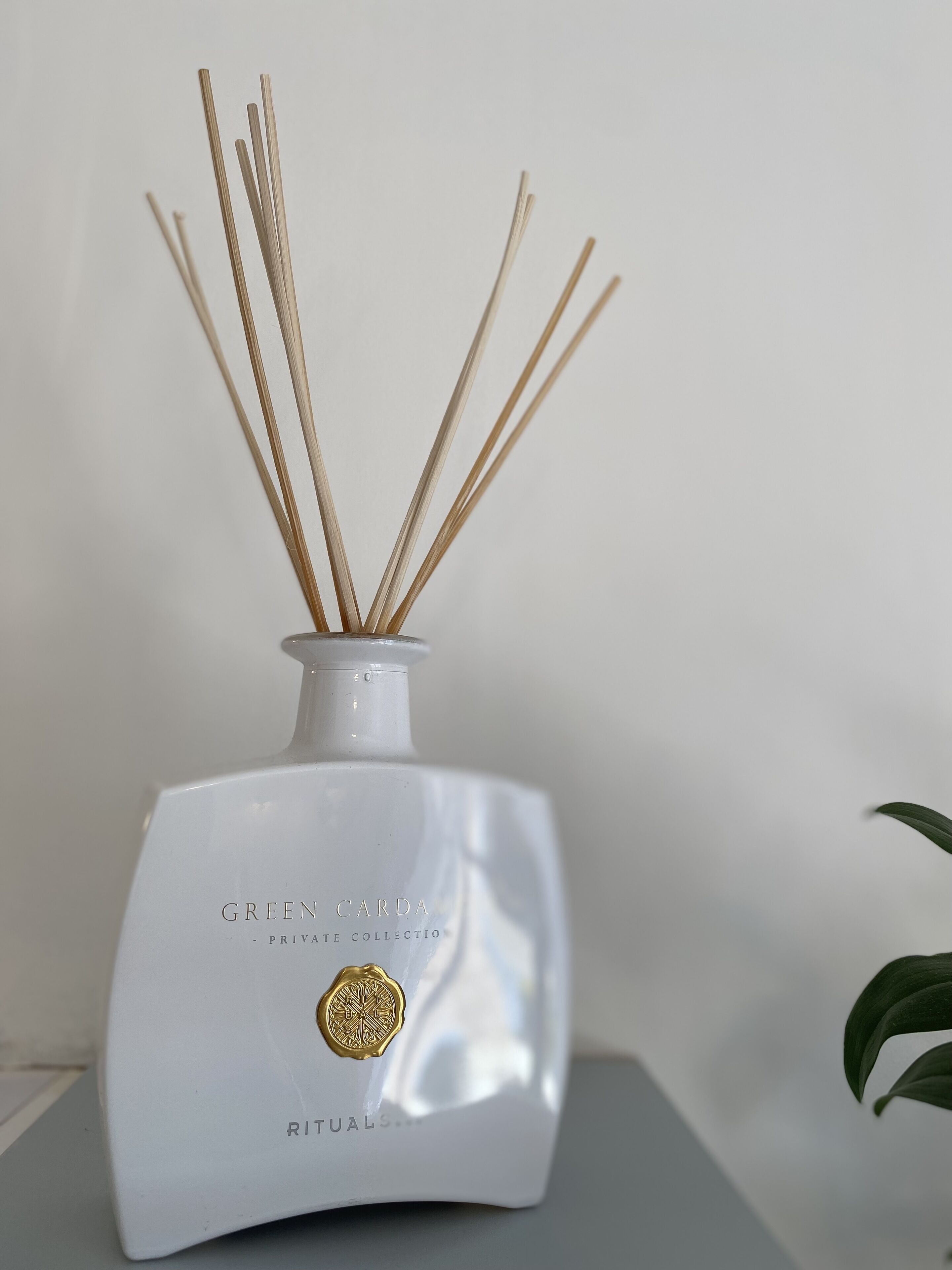 A white ceramic diffuser with reed sticks, labeled "GREEN CARDA PRIVATE COLLECTION RITUALS."