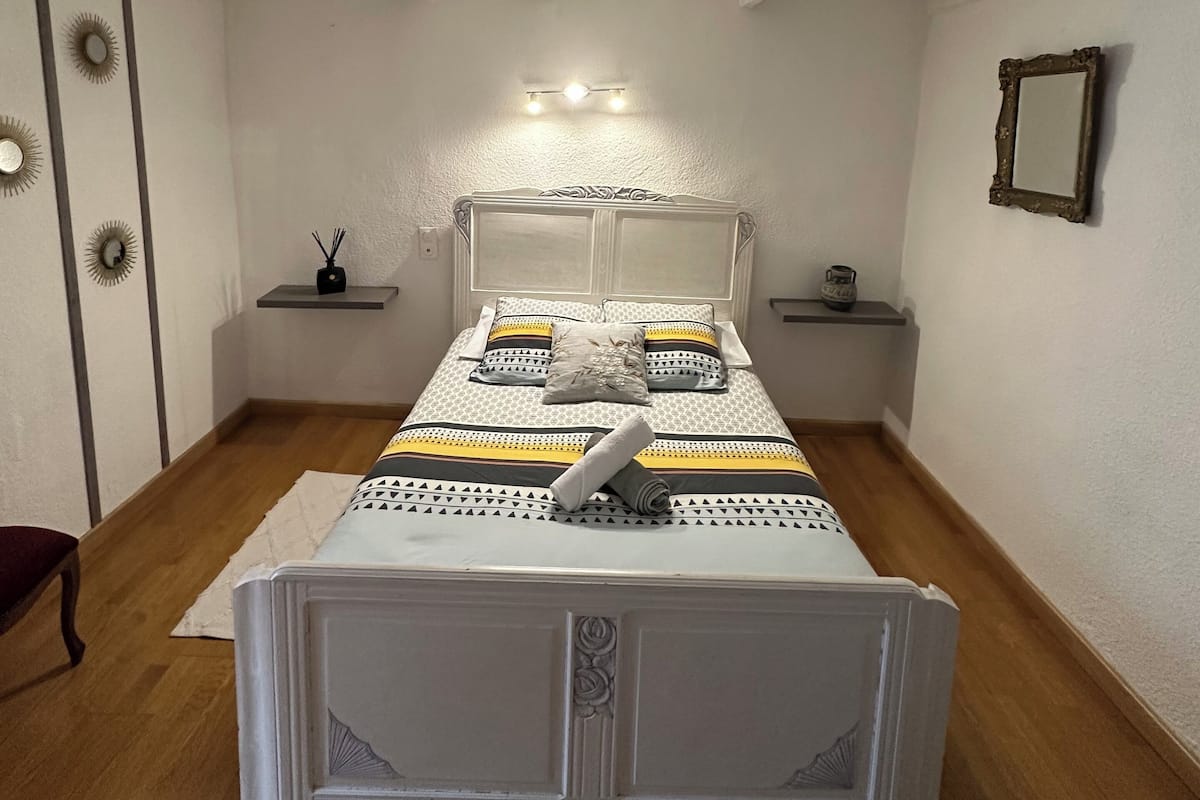 Une chambre bien rangée, avec un lit, des tables de chevet et un miroir au mur.