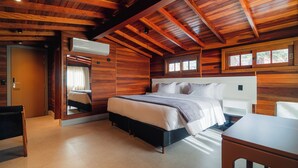 A wooden-paneled bedroom with a bed, a desk, and a mirror. - 249 DESIGN HOTEL (Gramado)
