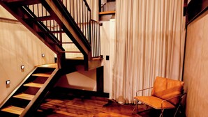 A staircase with wooden steps and metal railings, a leather chair, and a curtain. - 249 DESIGN HOTEL (Gramado)