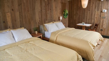 Een kamer met twee bedden, houten wanden, een klein tafeltje met een lamp en een hangende lamp.