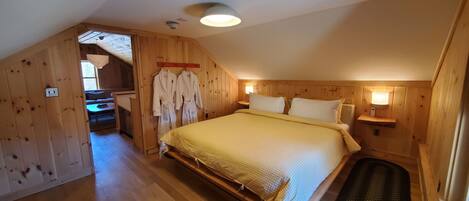 Un dormitorio con una cama grande, paredes de madera, suelo de madera e iluminación en el techo.
