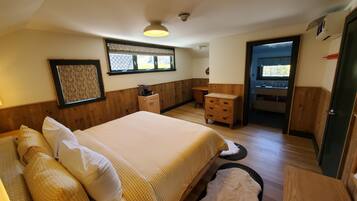 A bedroom with a bed, a dresser, a desk, and a window.
