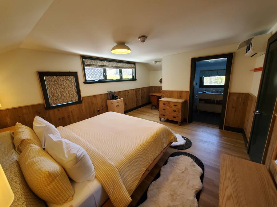 A bedroom with a bed, a dresser, a desk, and a window.