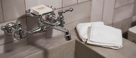 Un baño con un grifo cromado, un jabonera y una toalla blanca sobre una encimera.