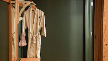 A wooden bench and a white robe hanging on a wooden rack in a room with a dark wall.