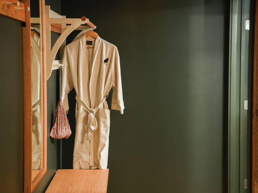 A wooden bench and a white robe hanging on a wooden rack in a room with a dark wall.