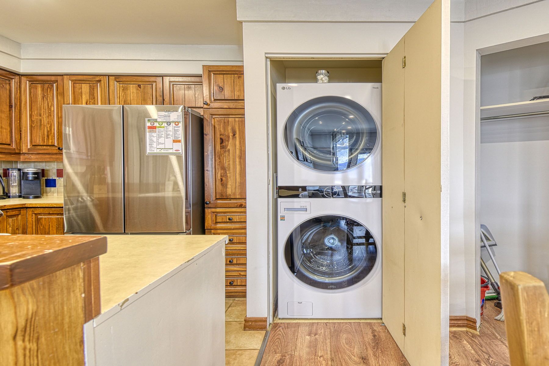 A compact kitchen with wooden cabinets, a stainless steel refrigerator, and a built-in washer and dryer.