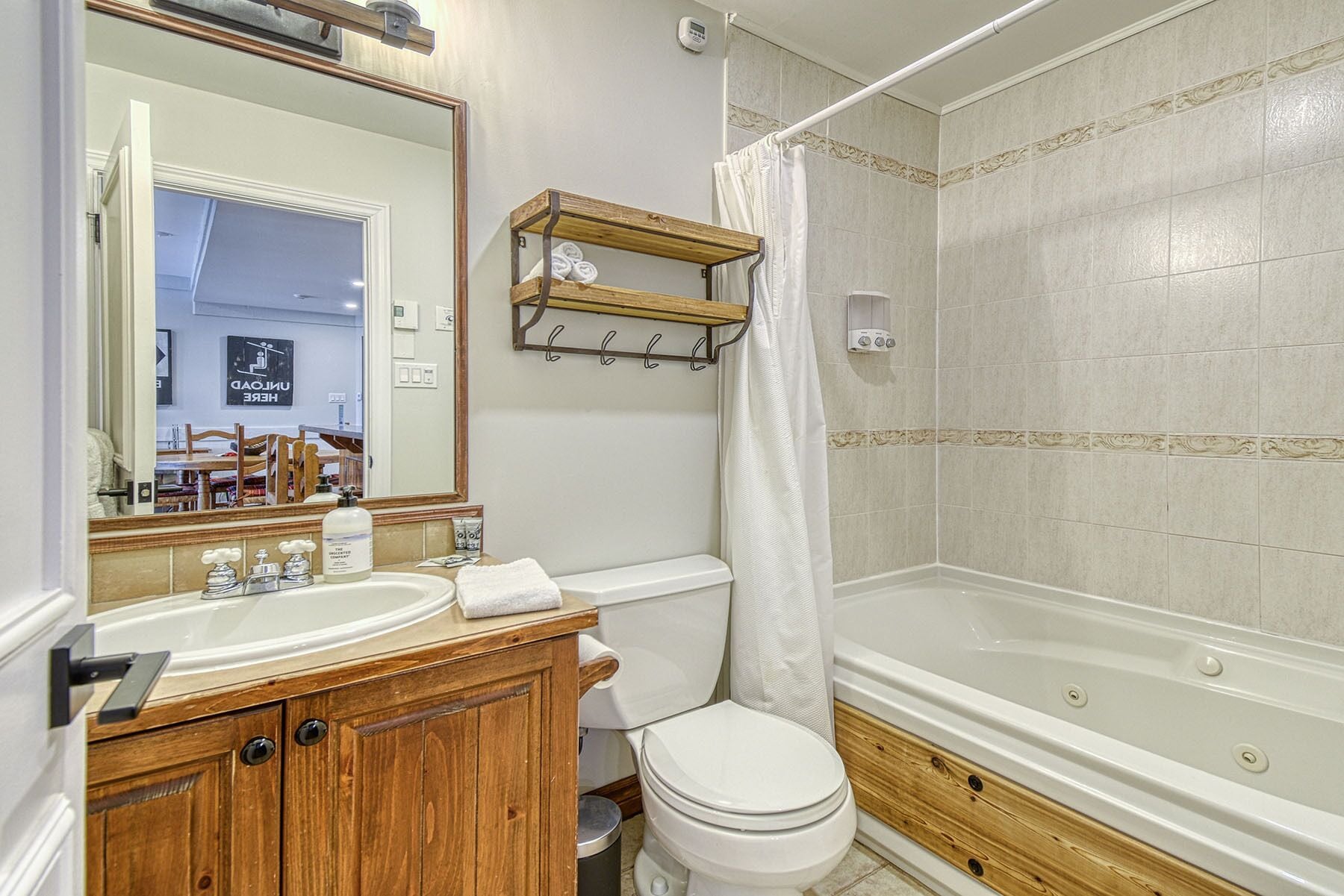 A bathroom with a wooden vanity, a white sink, a toilet, and a bathtub.