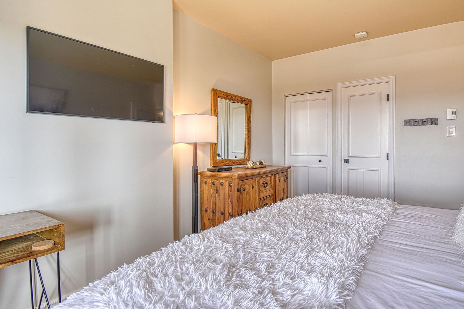 Un dormitorio con cama, cómoda, espejo y lámpara.