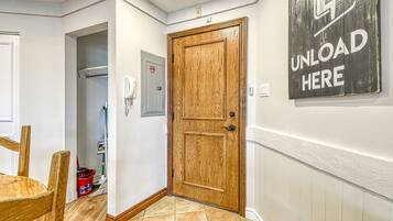 A hallway with a wooden door, a 'UNLOAD HERE' sign, a telephone, and a trash bin.