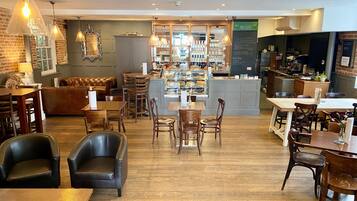 A cozy cafe with wooden furniture, a brick wall, and a counter with various items.