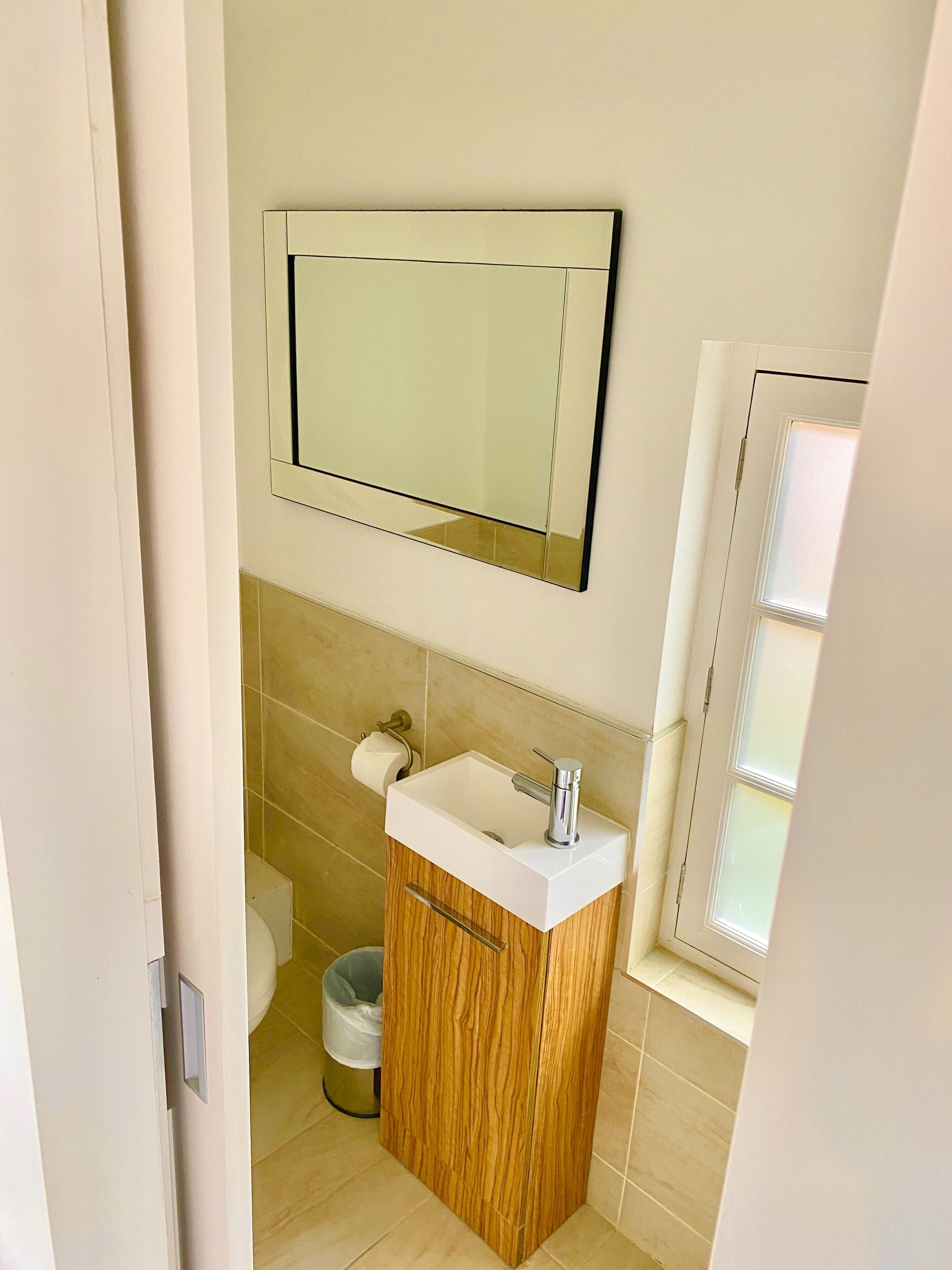 A bathroom with a wooden vanity, a sink, a mirror, and a toilet.