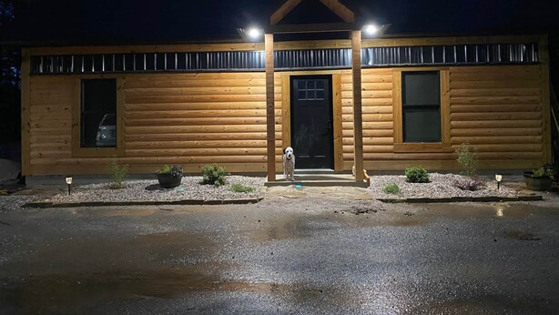 Eine Blockhütte mit Veranda, zwei Fenstern und einer Tür.