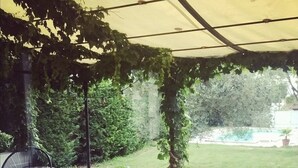 Une terrasse extérieure avec un sol carrelé, une table en bois et des chaises noires.