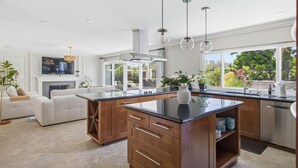 A modern kitchen with a central island, wooden cabinets, and pendant lighting. - 6BR SoCal Oasis with Pool Spa Sauna (Mission Viejo)