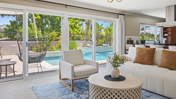 A modern living room with a pool view, a sofa, a chair, and a round table. - 6BR SoCal Oasis with Pool Spa Sauna (Mission Viejo)