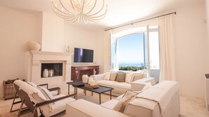 Een moderne woonkamer met een open haard, een televisie en een groot raam met uitzicht.