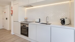 A modern kitchen with white cabinetry, a built-in oven, a toaster, and a sink.