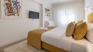 Habitación de hotel con cama, televisor de pantalla plana, obras de arte en las paredes y ventana con cortinas.
