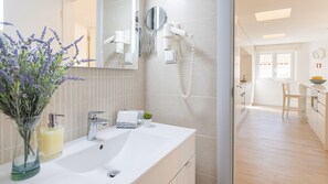 A modern bathroom with a white sink, a mirror, and a hairdryer mounted on the wall.
