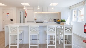 Una cocina moderna con una isla central, taburetes de bar y un ventanal con vistas.