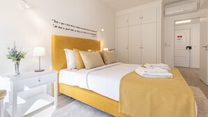 Una habitación de hotel con cama, mesita de noche, lámpara y una pared con una cita.