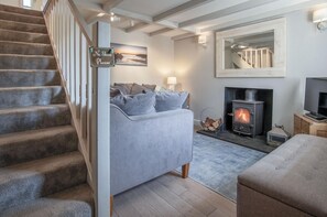 Relax in this inviting living room with a comfortable sofa, wood-burning stove, and flat-screen TV.