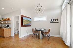 A modern kitchen with a dining area, a large window, and a unique chandelier.