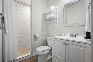 A bathroom with a shower, toilet, and white cabinets.