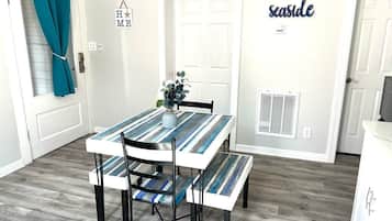 A dining area with a striped table, chairs, and a small plant.