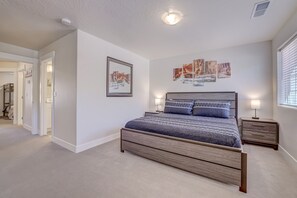 Une chambre à coucher avec un grand lit, une table de chevet, un miroir fixé au mur et des œuvres d’art.