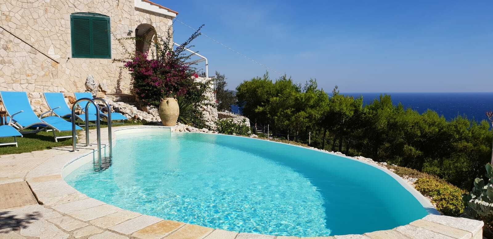 Ein Swimmingpool mit blauem Wasser, umgeben von Steinmauern und blauen Liegestühlen.