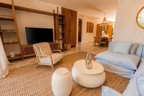A modern living room with a sofa, a TV, and a dining area. - 2BR Private Pool & Terrace in LOSANTOS (Tulum)